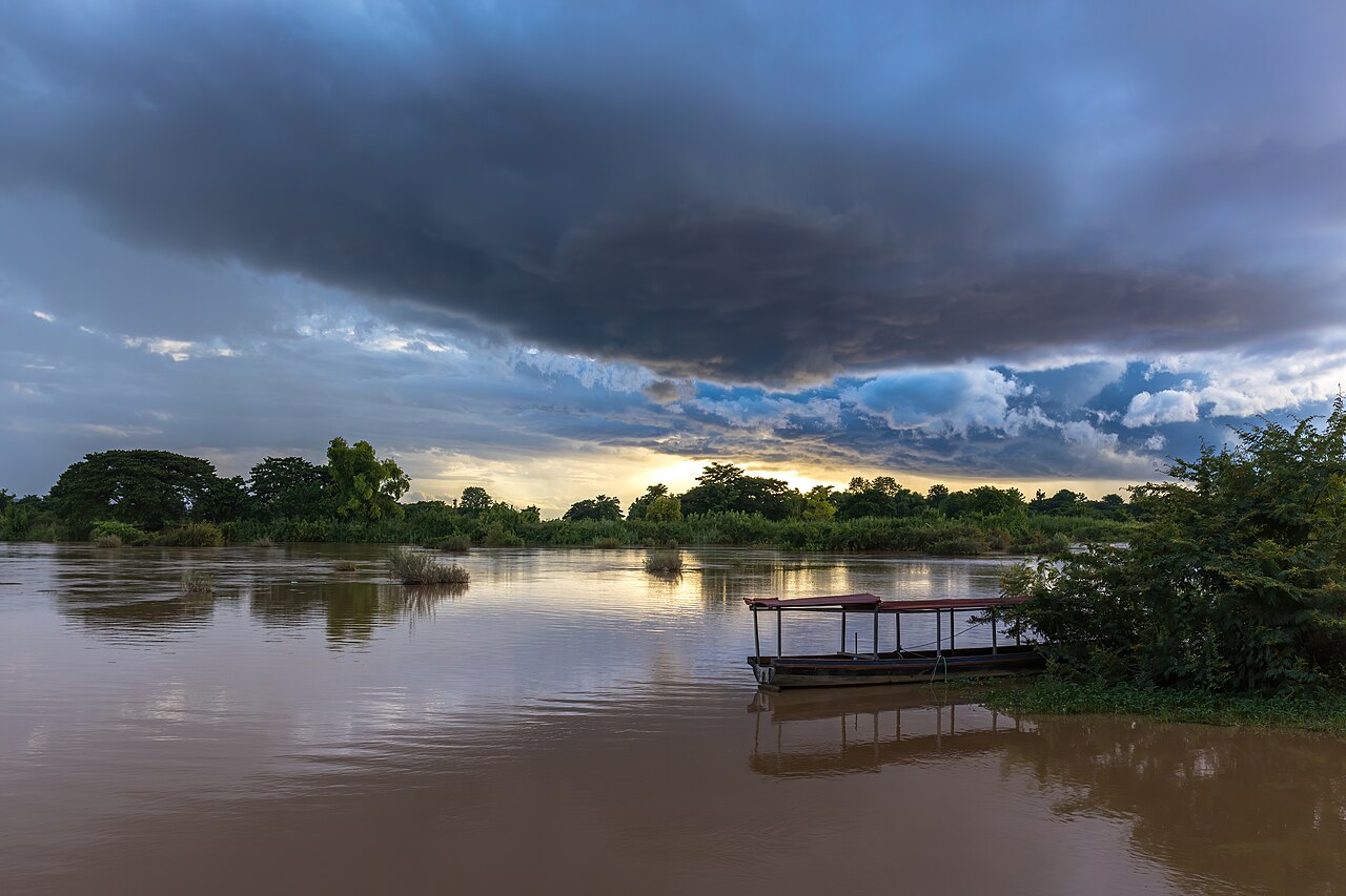 Blue stormy clouds at sunset with water reflection